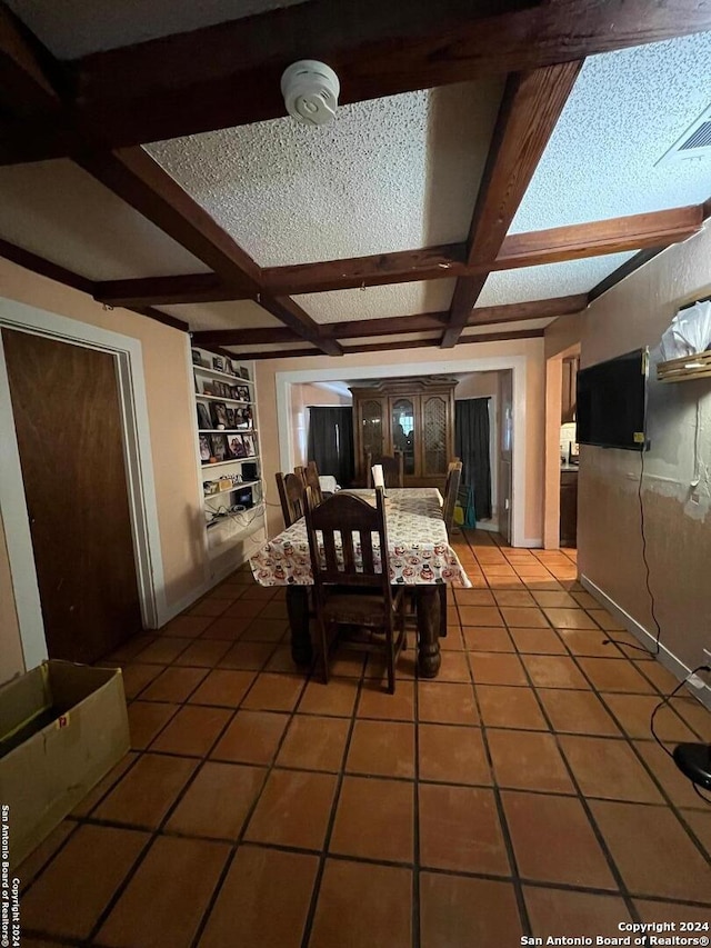 unfurnished dining area featuring a textured ceiling, built in shelves, beam ceiling, and tile patterned floors