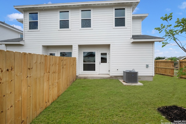 back of house with central AC unit and a yard