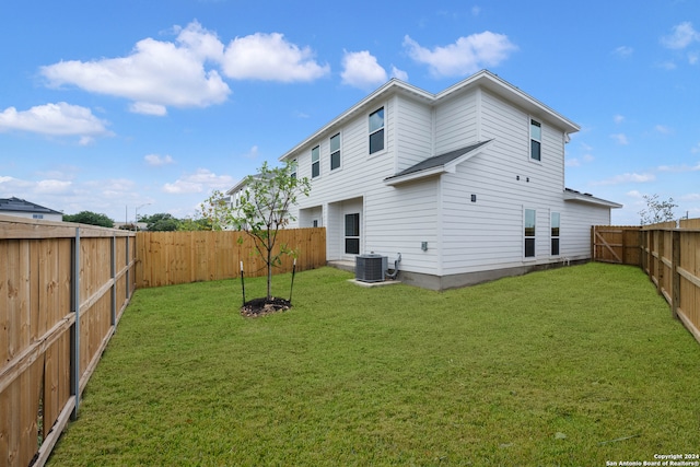 rear view of house featuring a lawn and central AC unit