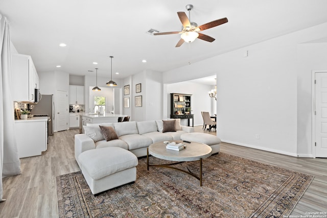 living room featuring sink, ceiling fan with notable chandelier, and light hardwood / wood-style floors