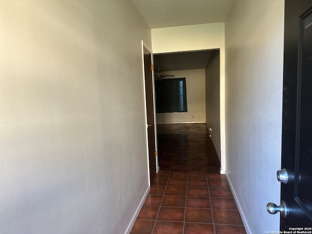 corridor featuring dark tile patterned floors and a textured ceiling