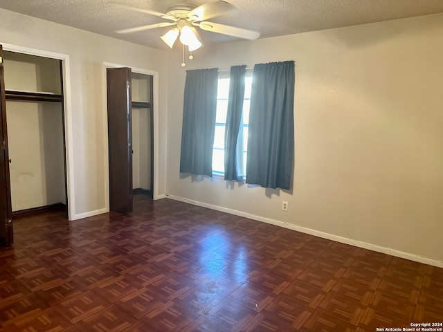 unfurnished bedroom with dark parquet floors, ceiling fan, and a textured ceiling