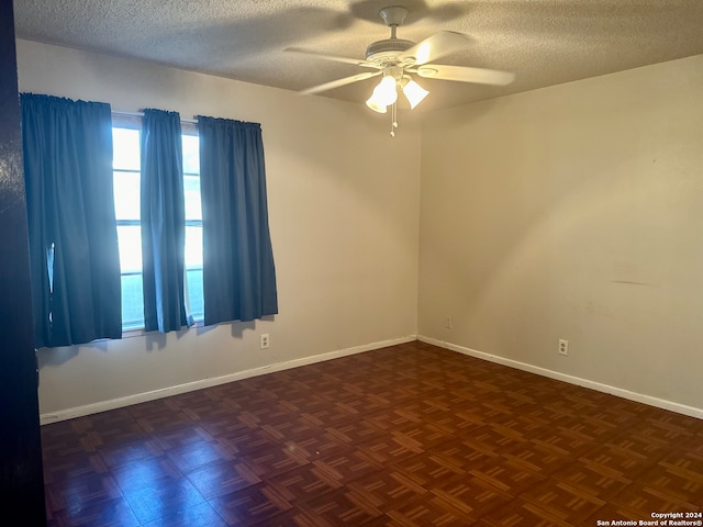 unfurnished room with dark parquet floors, ceiling fan, and a textured ceiling