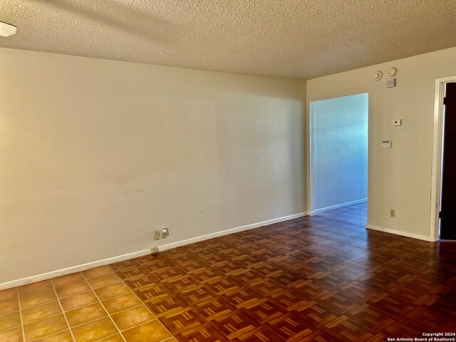 unfurnished room featuring a textured ceiling and parquet floors