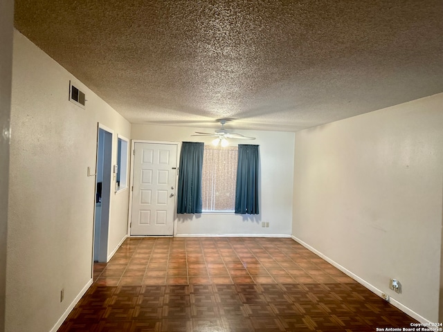 unfurnished room with ceiling fan, a textured ceiling, and dark parquet floors