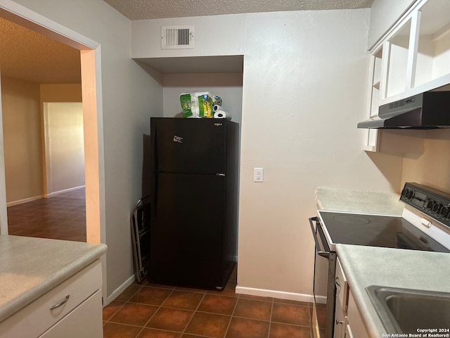 kitchen featuring white cabinetry, electric range, a textured ceiling, dark tile patterned floors, and black fridge