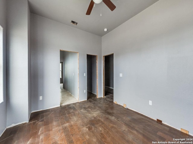 spare room with visible vents, ceiling fan, a towering ceiling, and wood finished floors