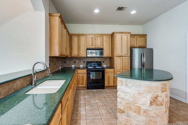 kitchen with appliances with stainless steel finishes, light tile patterned flooring, tasteful backsplash, a kitchen island, and sink