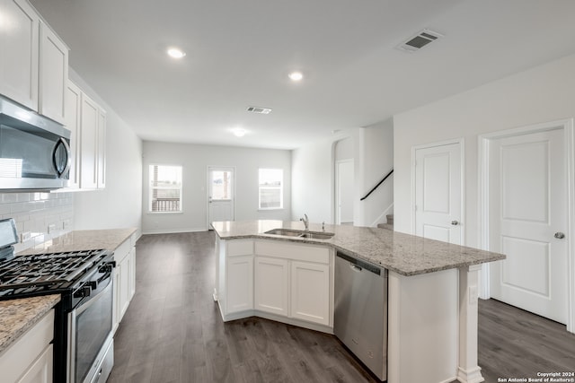 kitchen with appliances with stainless steel finishes, white cabinets, a center island with sink, hardwood / wood-style floors, and sink