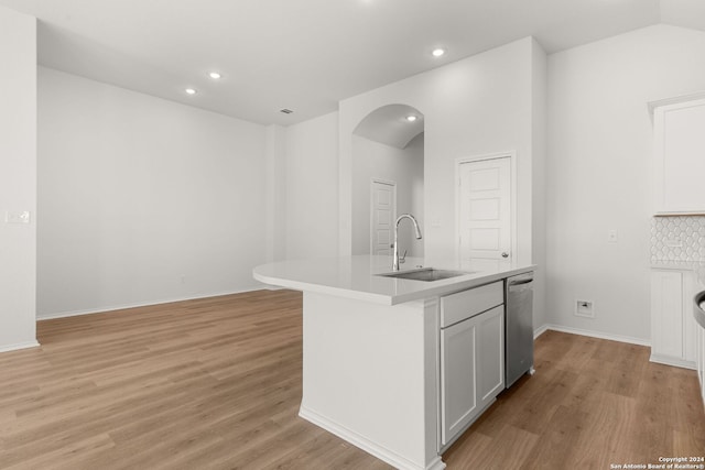 kitchen with sink, tasteful backsplash, stainless steel dishwasher, a center island with sink, and light wood-type flooring