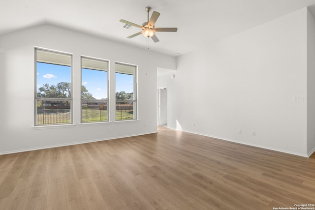 spare room with ceiling fan, vaulted ceiling, and light wood-type flooring