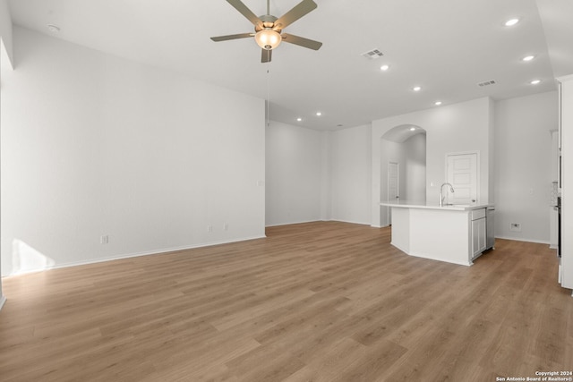 unfurnished living room featuring light wood-type flooring, ceiling fan, and sink