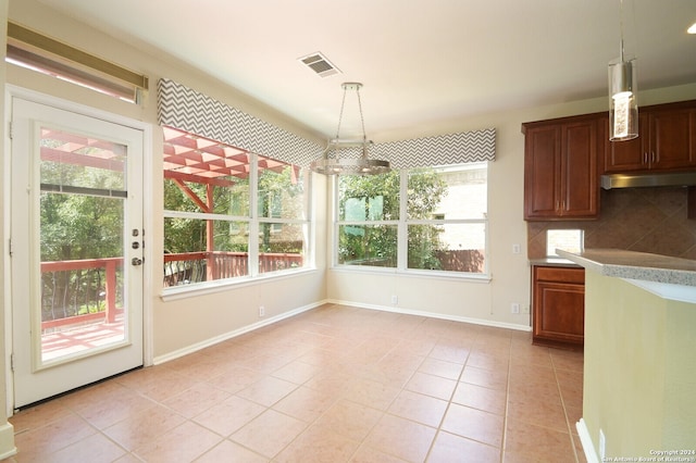 unfurnished dining area featuring a notable chandelier, light tile patterned flooring, and plenty of natural light