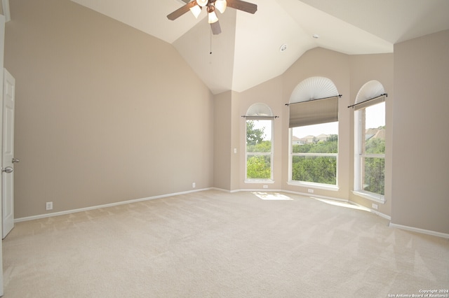 carpeted spare room with ceiling fan and high vaulted ceiling