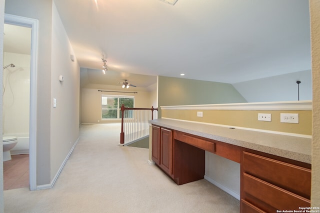 interior space with built in desk, lofted ceiling, ceiling fan, and light colored carpet