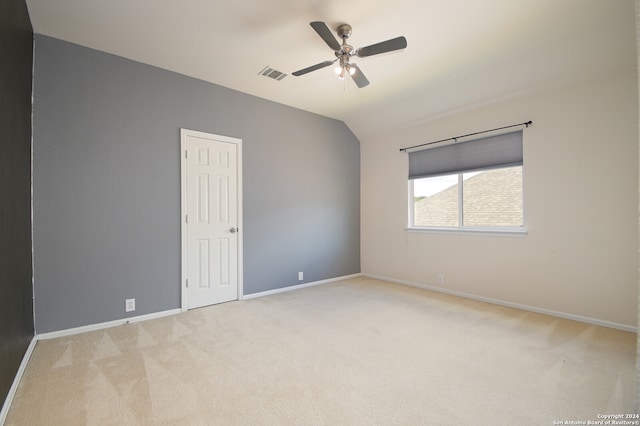 empty room featuring light carpet, vaulted ceiling, and ceiling fan