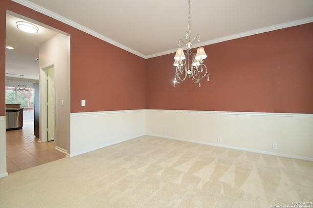 spare room with carpet floors, a notable chandelier, and ornamental molding