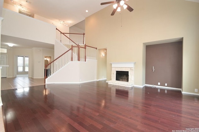 10606 Rainbow Vw, Helotes, TX 78023 - unfurnished living room featuring ceiling fan, a fireplace, wood finished floors, and a towering ceiling