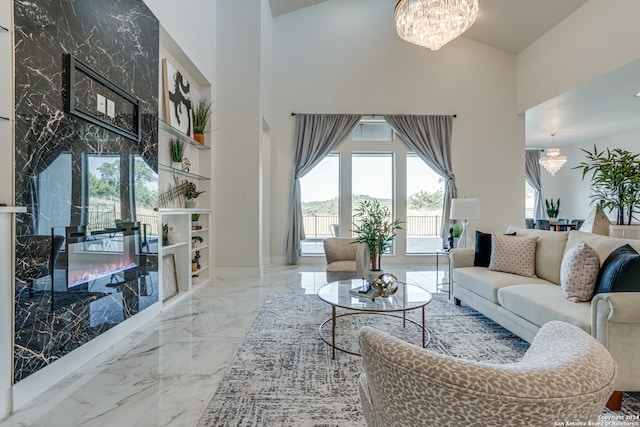 living room with a notable chandelier, a premium fireplace, and high vaulted ceiling