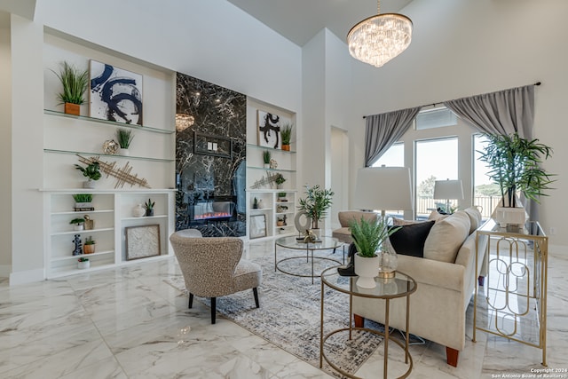 living room with built in features, a high ceiling, a high end fireplace, and a chandelier