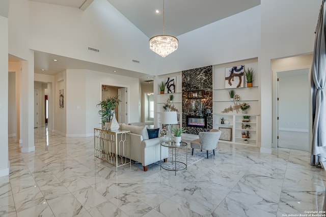 living room featuring built in features, a fireplace, high vaulted ceiling, and an inviting chandelier