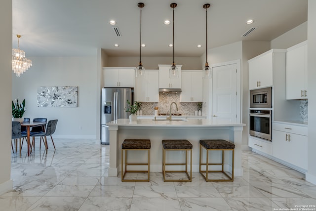 kitchen with white cabinets, sink, hanging light fixtures, an island with sink, and stainless steel appliances