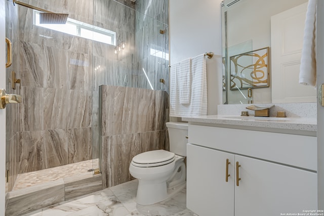 bathroom with vanity, toilet, a tile shower, and tile walls