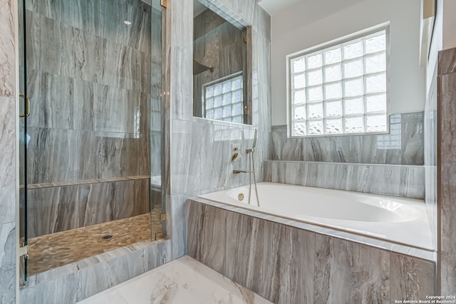 bathroom with tile walls and independent shower and bath