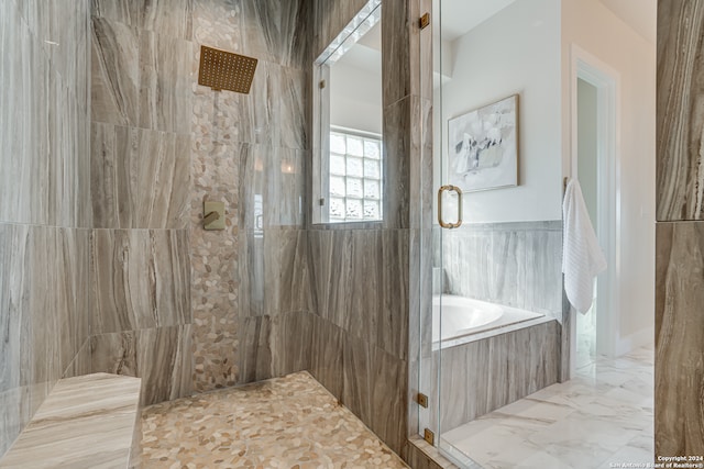 bathroom with shower with separate bathtub and tile walls