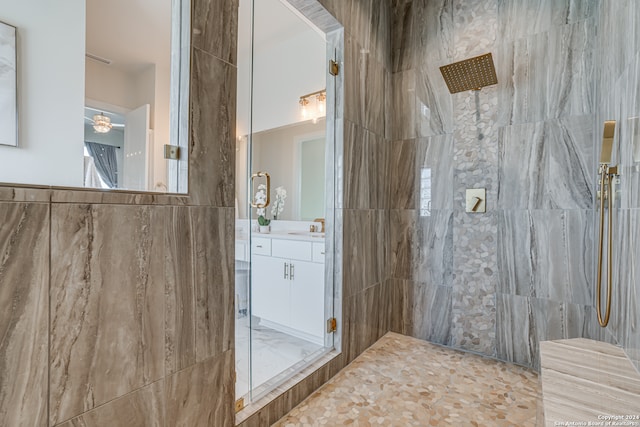 bathroom with vanity, tiled shower, and tile walls