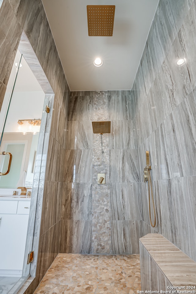 bathroom featuring tiled shower, vanity, washer / clothes dryer, and tile walls