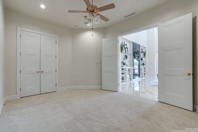 unfurnished bedroom featuring light carpet, a closet, and ceiling fan