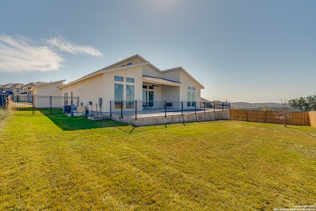 rear view of property featuring a lawn and ceiling fan