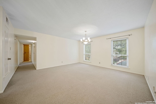 empty room with a chandelier and light colored carpet