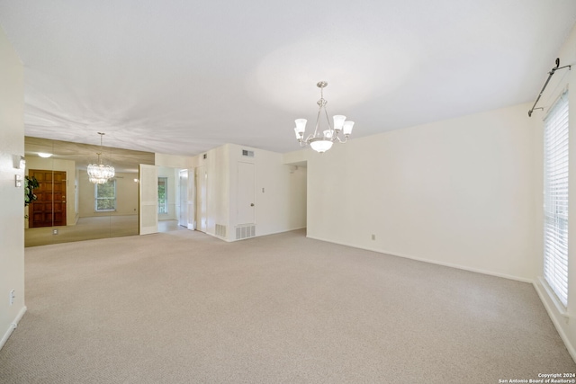 unfurnished living room with an inviting chandelier and light colored carpet