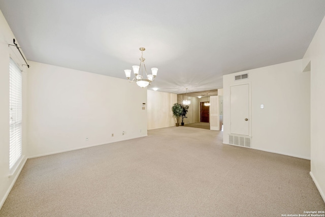 carpeted spare room featuring plenty of natural light and a chandelier