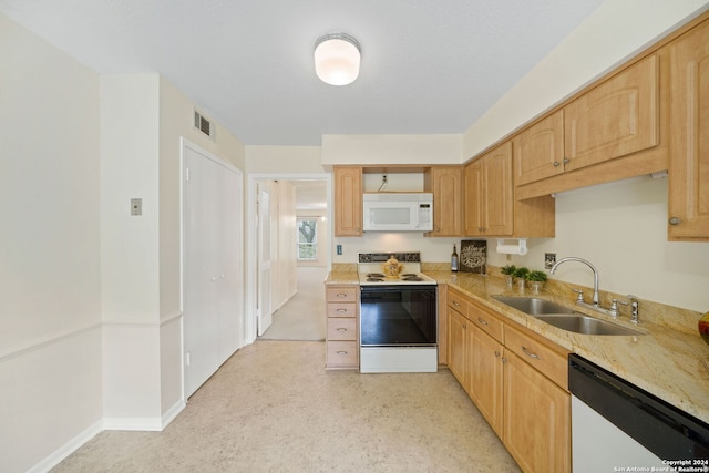 kitchen with white appliances, light brown cabinetry, and sink