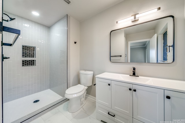 bathroom with a tile shower, vanity, and toilet