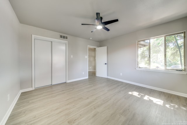 unfurnished bedroom with light hardwood / wood-style floors, ceiling fan, and a closet