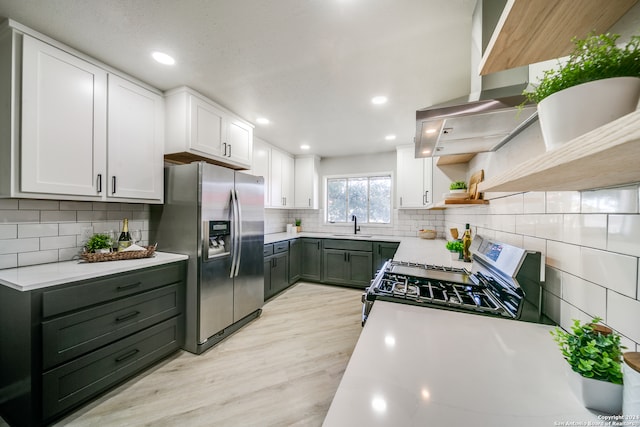 kitchen featuring appliances with stainless steel finishes, decorative backsplash, light hardwood / wood-style floors, and white cabinets