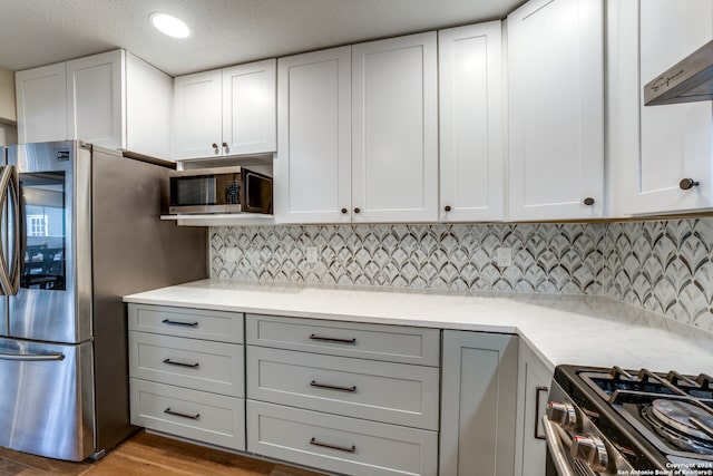 kitchen featuring ventilation hood, white cabinets, light wood-type flooring, and appliances with stainless steel finishes