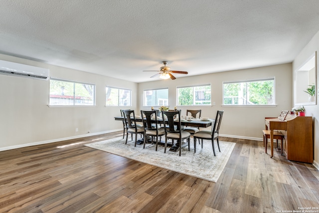 dining area with ceiling fan, plenty of natural light, hardwood / wood-style floors, and a wall mounted air conditioner