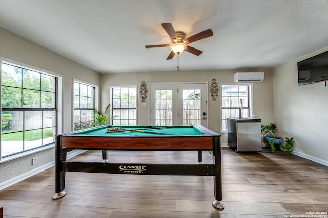 rec room with a textured ceiling, ceiling fan, a wall mounted AC, billiards, and hardwood / wood-style floors