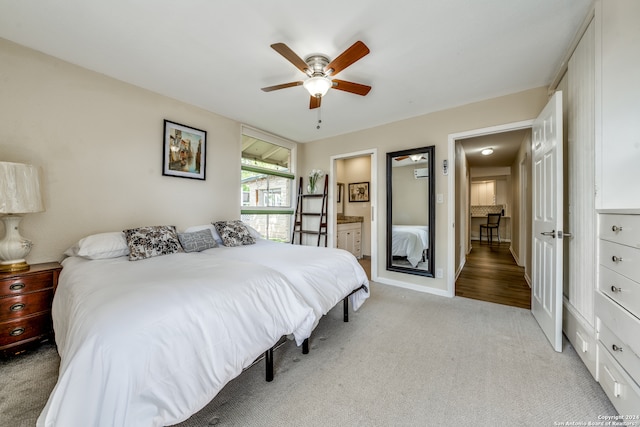 bedroom with light carpet, ensuite bathroom, and ceiling fan