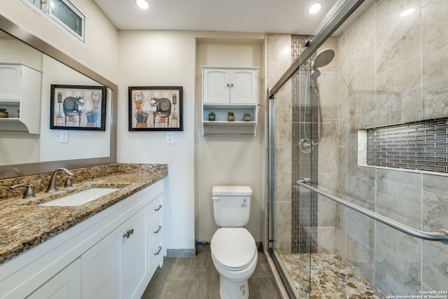 bathroom featuring tile patterned flooring, vanity, toilet, and an enclosed shower