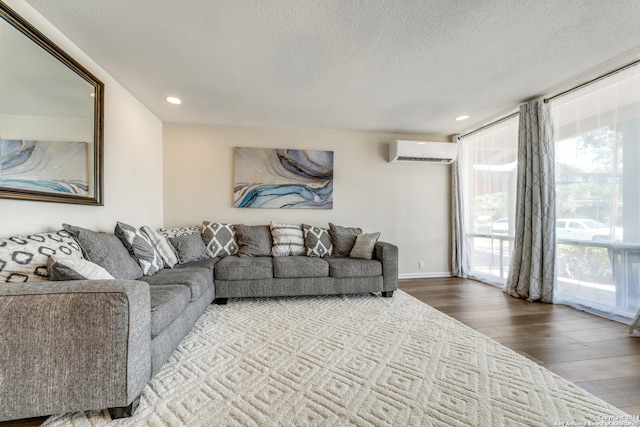 living room featuring a textured ceiling, hardwood / wood-style flooring, and a wall unit AC