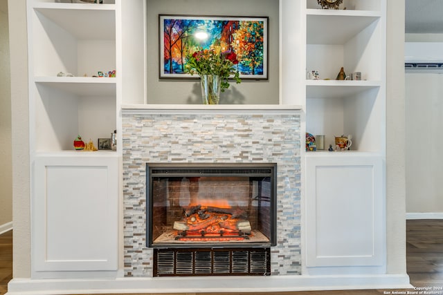 room details featuring built in shelves, hardwood / wood-style floors, and a tiled fireplace