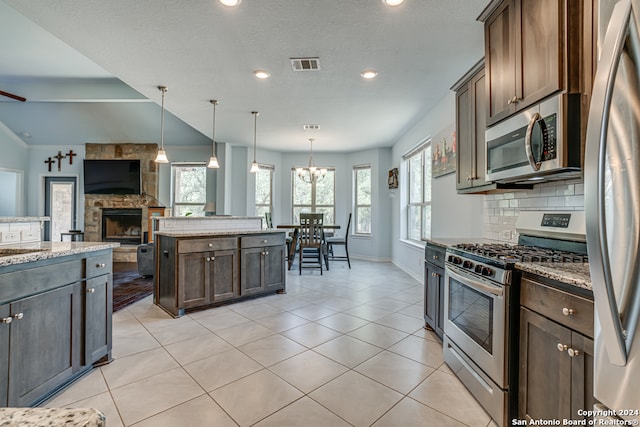 kitchen featuring light stone counters, stainless steel appliances, a fireplace, and dark brown cabinetry