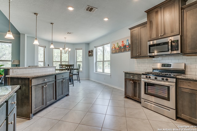 kitchen featuring light stone countertops, stainless steel appliances, a chandelier, and decorative light fixtures