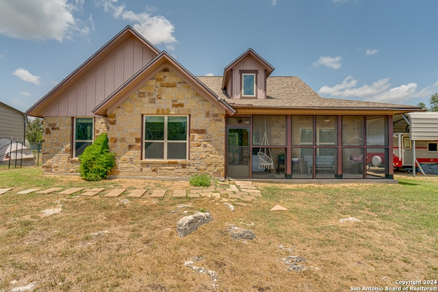 rear view of house featuring a sunroom and a yard